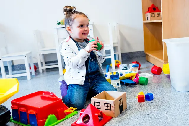 Barn som smiler med lekeklosser i hånden. Foto.