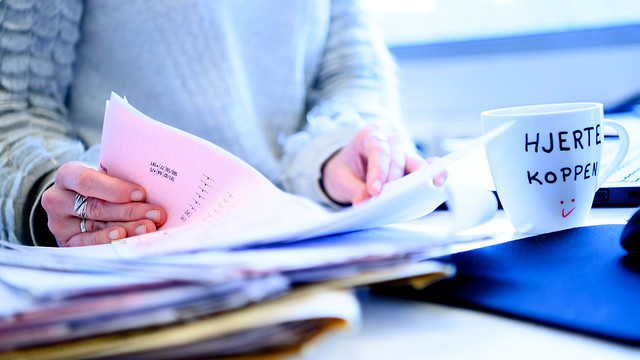 Bilde av hender som blar i en rapport.