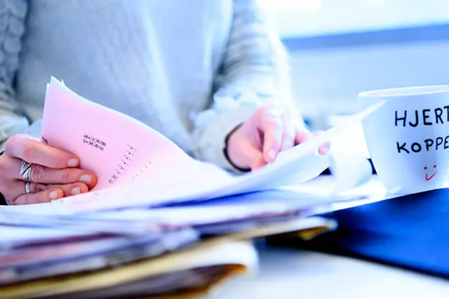 Bilde av hender som blar i en rapport.