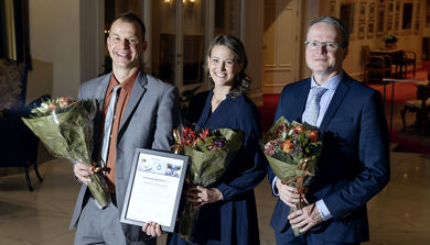 Tre personer med blomster og diplom i hendene.