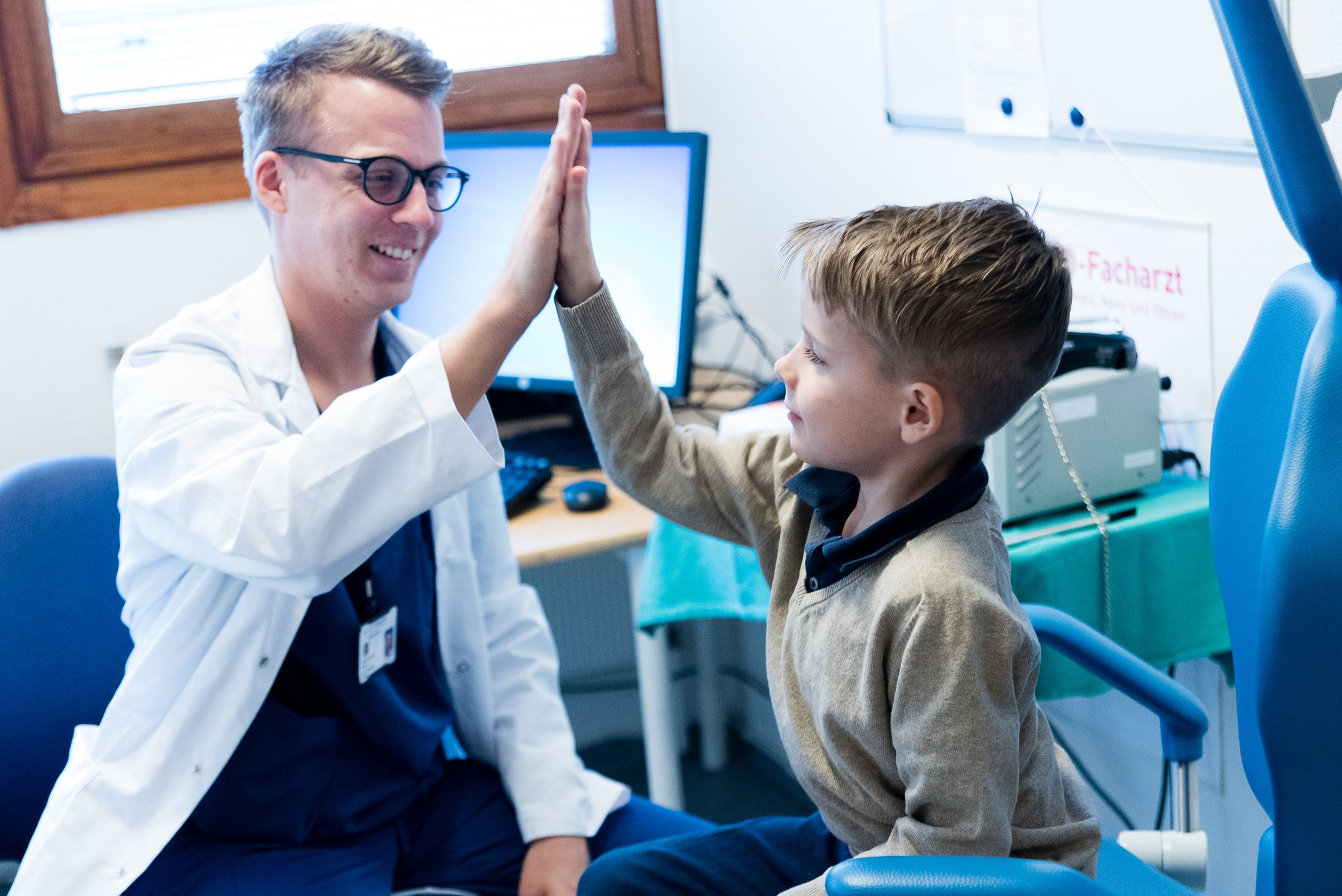 En lege og en gutt som gir hverandre high five