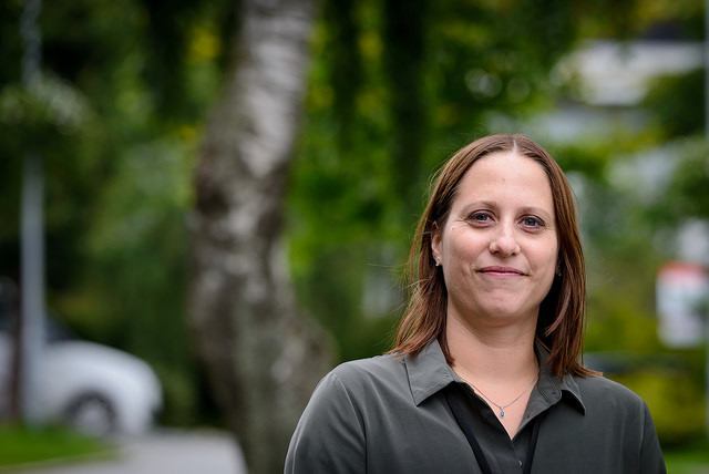 En kvinne smiler med trær i bakgrunnen