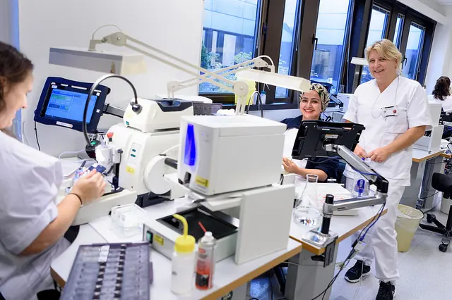 Tre kvinner smiler og jobber.