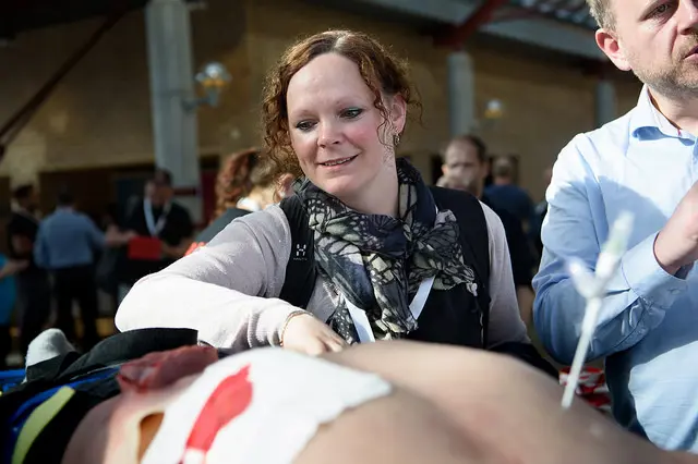 En kvinne står over en simuleringsdukke.