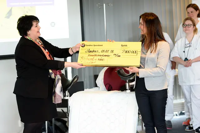 To kvinner holder i en sjekk lydende to millioner kroner.