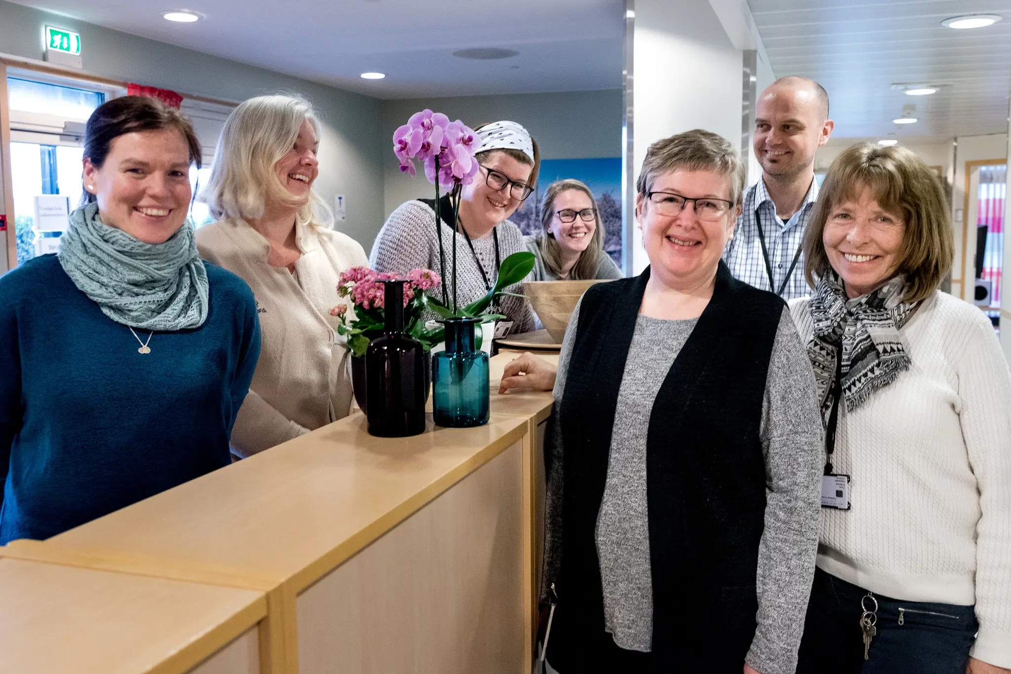 En gruppe mennesker som står rundt en skranke