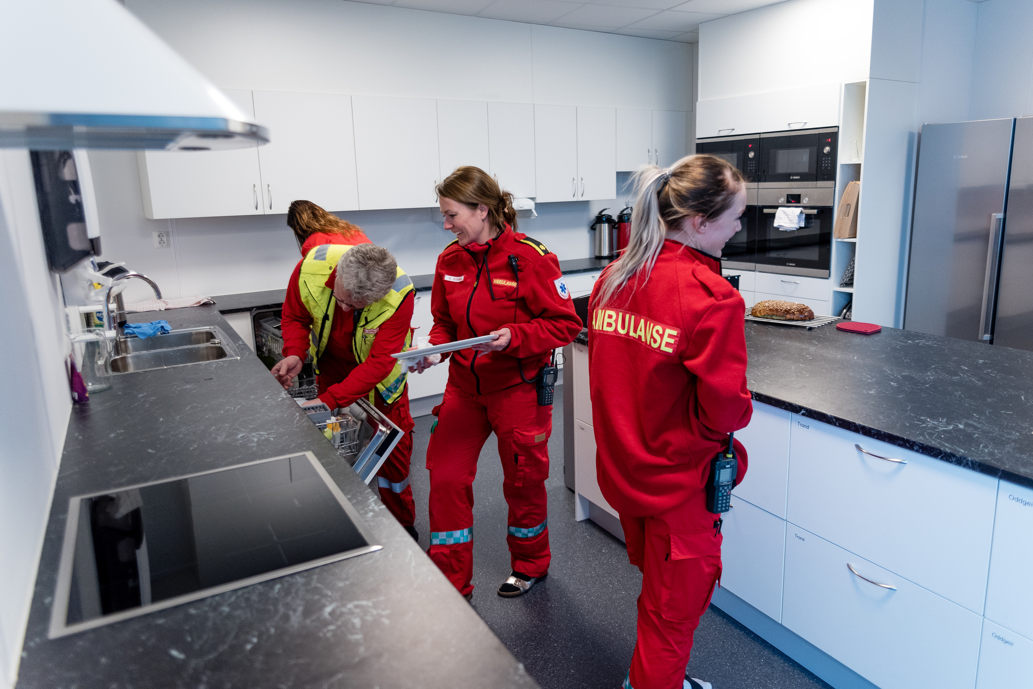 En gruppe kvinner i røde frakker på et kjøkken