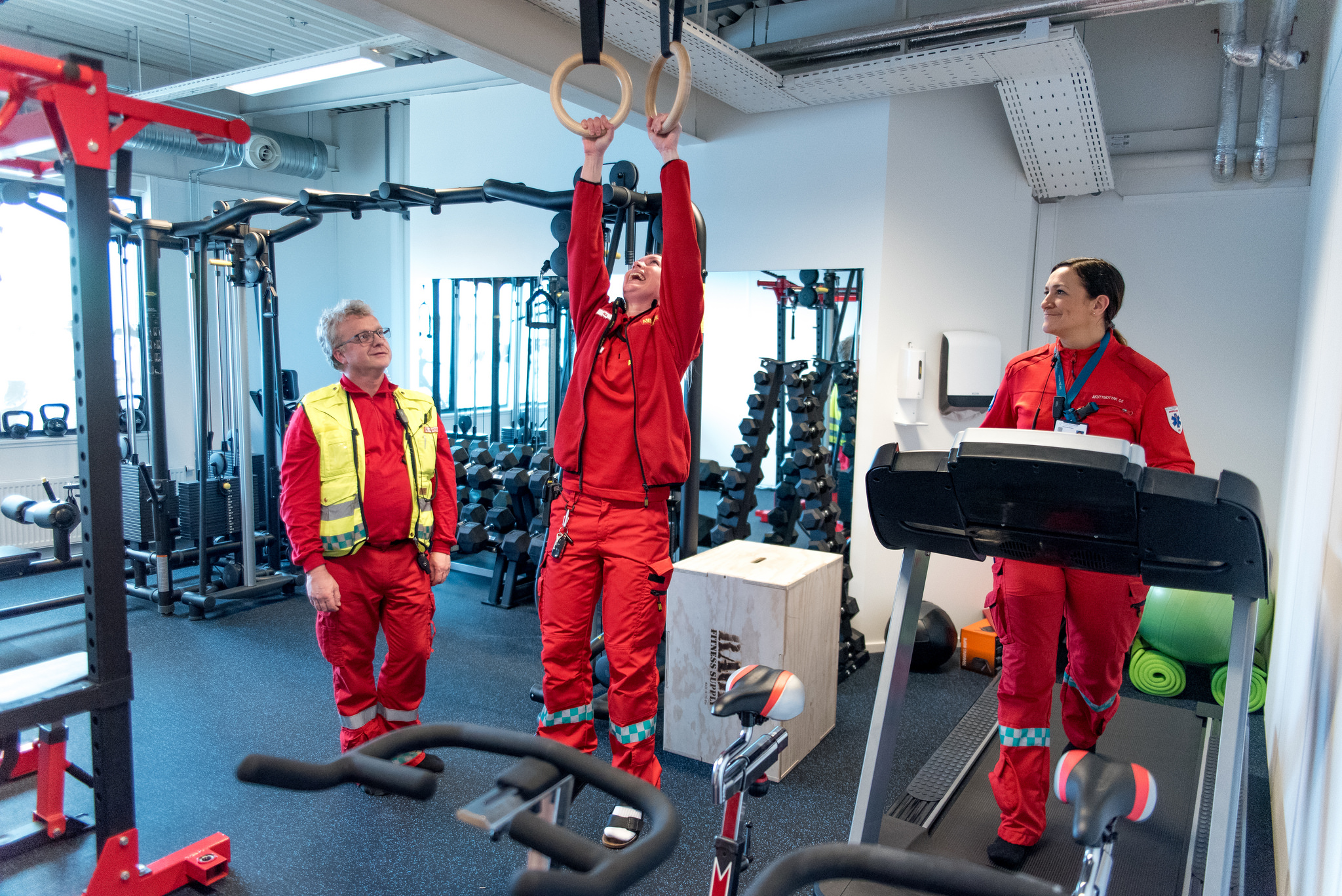 Noen få mennesker i røde jumpsuits som jobber på en fabrikk