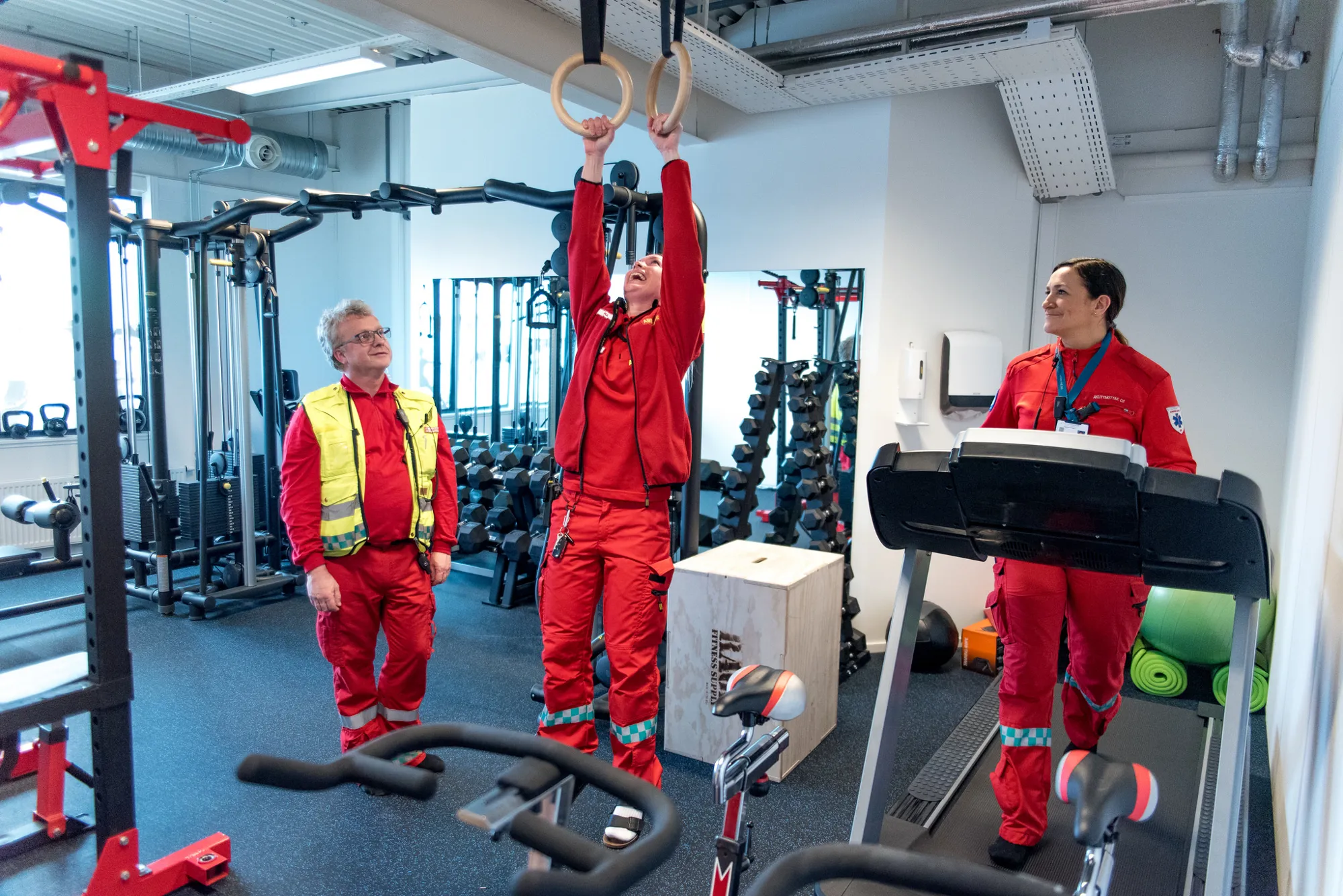 Noen få mennesker i røde jumpsuits som jobber på en fabrikk