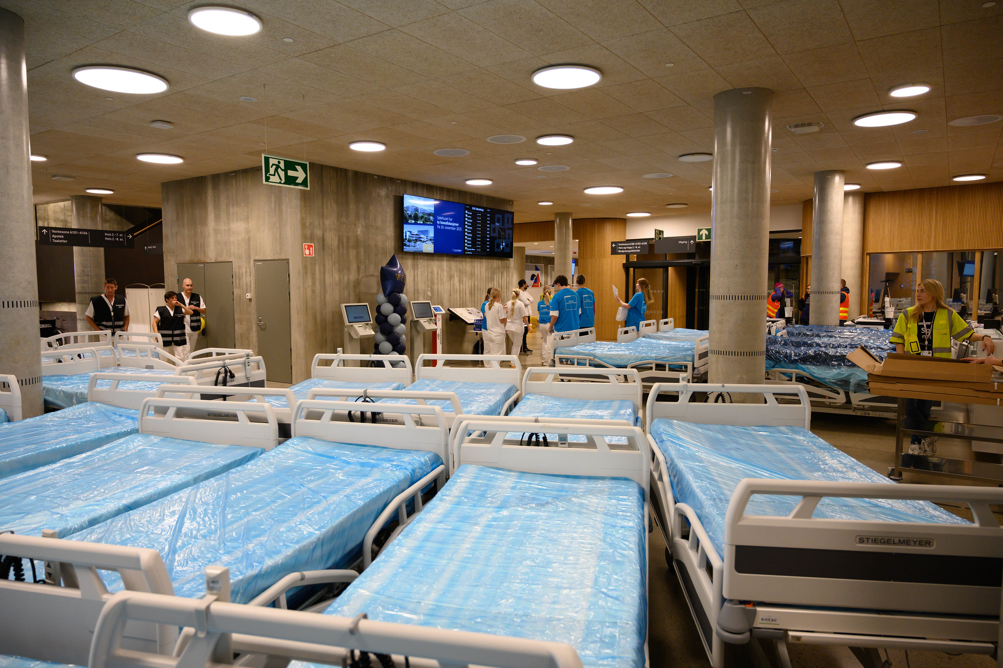 En gruppe mennesker i et rom med blå og hvite senger